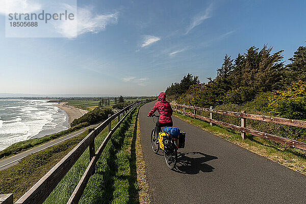 Radfahrerin fährt mit dem Fahrrad auf der Straße über die Meeresküste