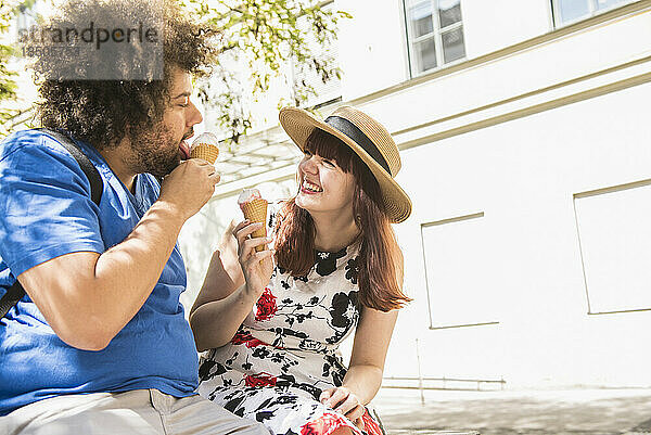 Glückliches junges Paar  das draußen Eistüten isst
