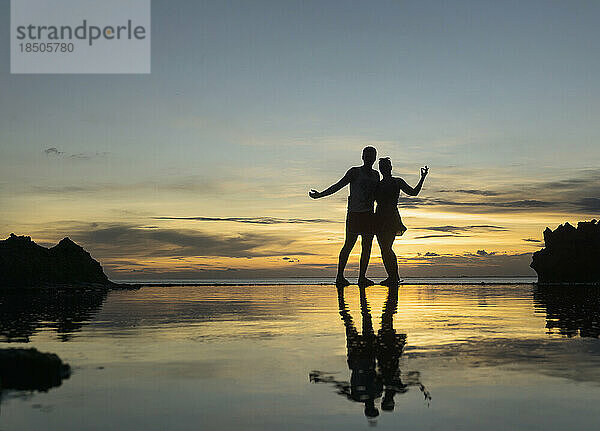 Silhouette eines Paares  das sich bei Sonnenuntergang am Strand umarmt  Nusa Lembongang  Bali  Indonesien