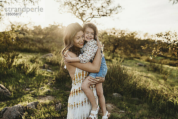 Schöne Mutter hält ihre kleine Tochter im hellen Grasland