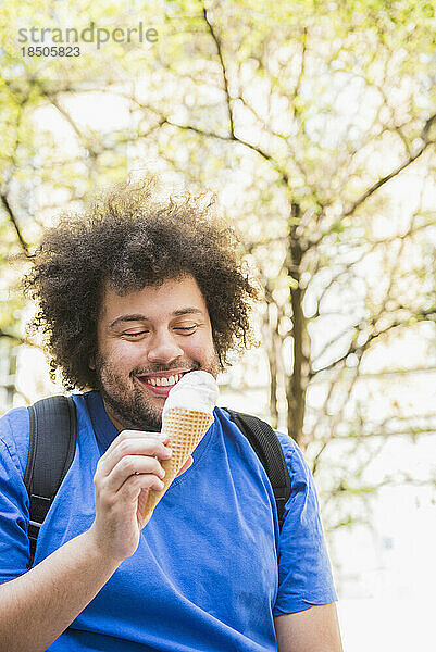 Glücklicher junger Mann  der Eis isst
