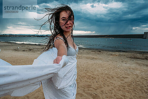 Teenager-Mädchen tanzt an einem stürmischen Tag am Strand