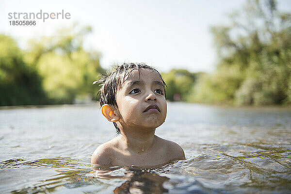 Lateinamerikanisches Kind genießt in Ruhe den Sommer in einem Fluss