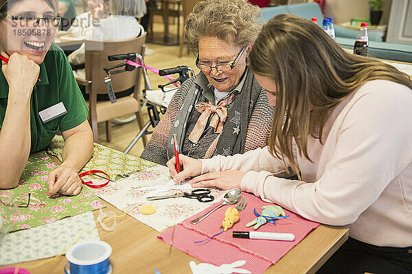 Ältere Frauen mit Mädchen und Krankenschwester machen handwerkliche Aktivitäten im Erholungsheim