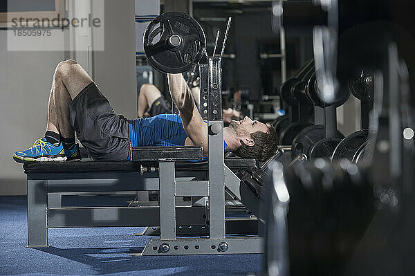 Mittlerer erwachsener Mann beim Bankdrücken im Fitnessstudio  Bayern  Deutschland