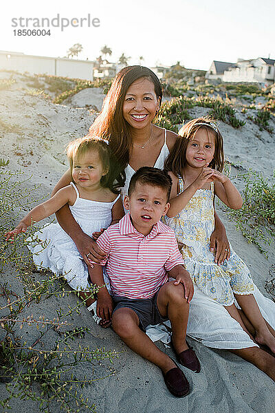 Mutter posiert mit ihren drei Kindern am Strand von San Diego
