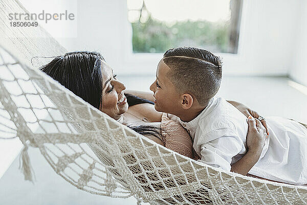 Mutter und kleiner Sohn schauen einander an  während sie in der Hängematte liegen