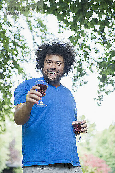 Glücklicher junger Mann im Freien mit einem Glas Wein