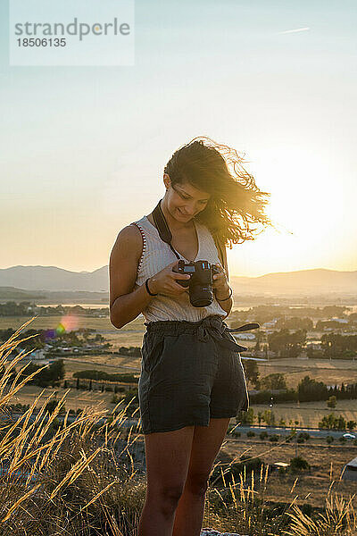 Eine junge Frau betrachtet ihre Bilder mit ihrer Kamera auf einem Berggipfel