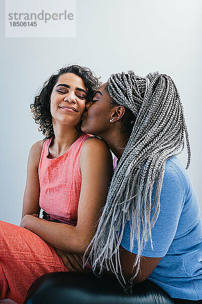 Lesbische Frau küsst Freundin  während sie zu Hause sitzt