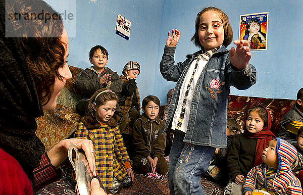Ein Mädchen tanzt  während eine Lehrerin in einer Kindertagesstätte in Kabul einen Rhythmus vorgibt.