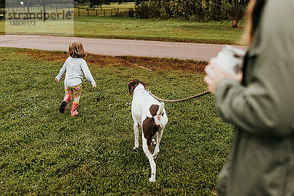 Familie geht im Herbst spielerisch mit Hund auf örtlichem Wanderweg nach draußen