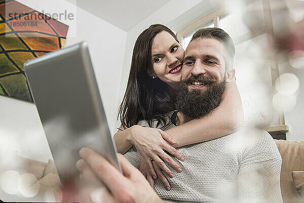 Paar umarmt und schaut digitales Tablet an