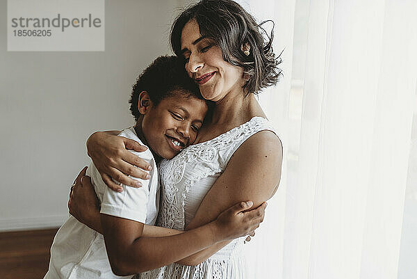 Mutter umarmt ihren schulpflichtigen Sohn lächelnd im Studio