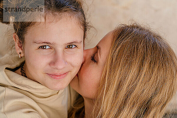 Nahaufnahmeporträt einer lächelnden Mutter und ihrer Tochter im Teenageralter.