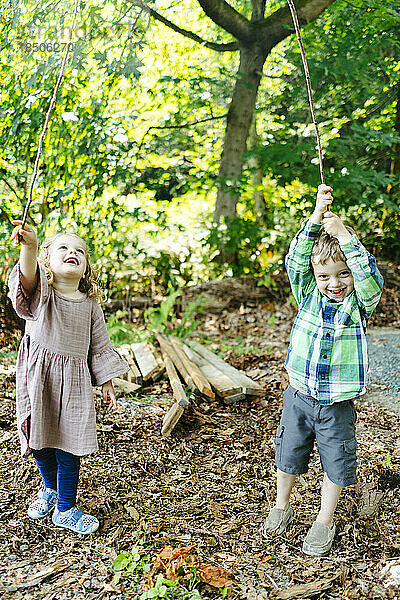 Geradeaus Porträt eines Mädchens und eines Jungen  die im Wald spielen
