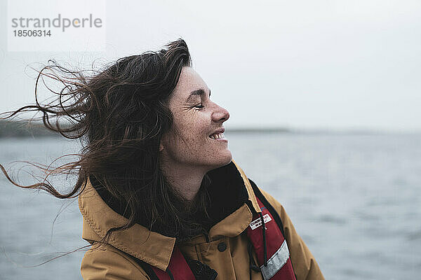 Profil einer glücklichen Frau mit Sommersprossen  die auf einem Boot in Schottland lächelt