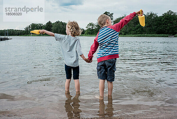 Bruder und Schwester halten sich an den Händen und spielen im Urlaub gemeinsam im Meer