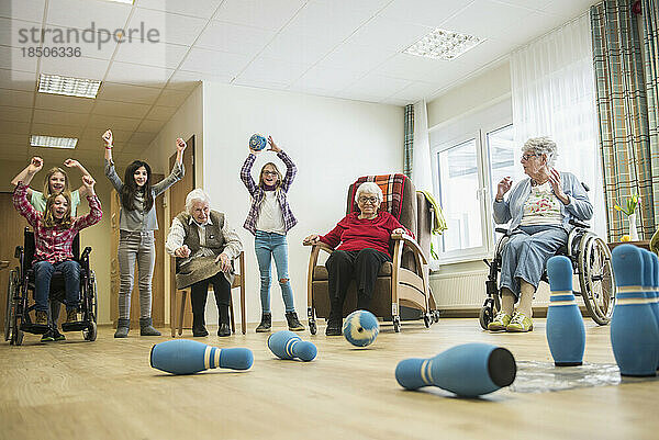 Mädchen spielen Bowling mit älteren Frauen im Seniorenheim