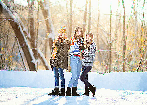 Drei kleine Mädchen trinken an einem Wintertag Kaffee im Schnee.