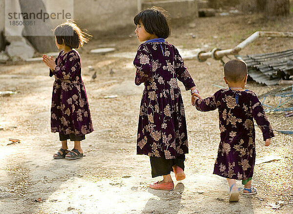 Drei Mädchen in Kleidern aus demselben Stoff gehen in den Kabuler Zoo.