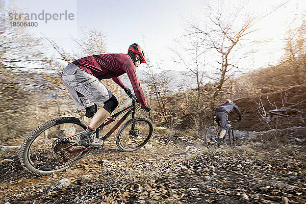 Mountainbiker fahren bergab in alpiner Landschaft  Trentino  Italien