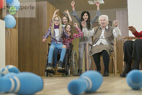 Mädchen spielen Bowling mit Seniorin im Pflegeheim
