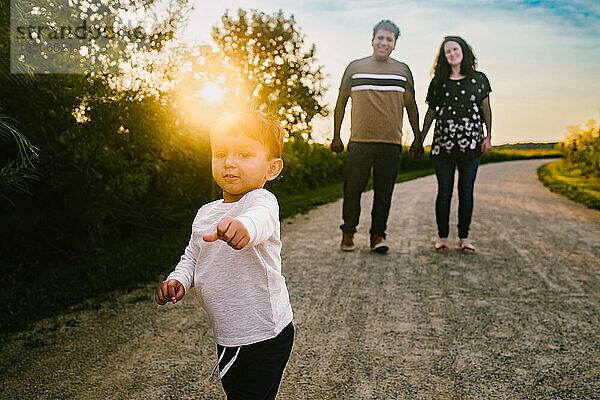 Kleinkinder hispanischer Junge spielt mit Eltern auf Wanderung im goldenen Sonnenschein