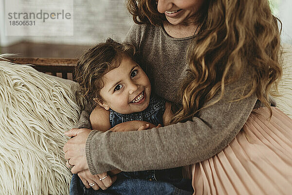 Nahaufnahme Porträt eines jungen Mädchens  das lächelt  während die Mutter sie hält