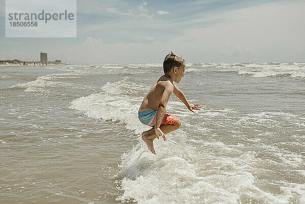 Junge springt in den Meereswellen am Strand in Corpus Christi  Texas