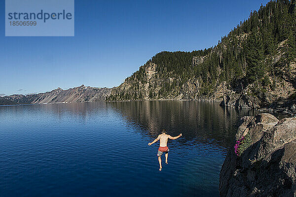 Ein junger Mann springt in das kalte  klare Wasser des Crater Lake.