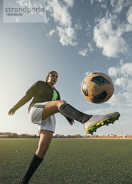 Junge Fußballspielerin kickt Ball in einem Stadion. Selektiver Fokus.