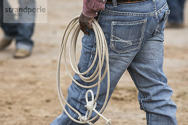 Ein Cowboy trägt sein Seil hinter der Bühne beim Arizona Black Rodeo