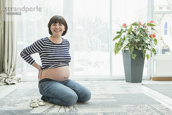 Porträt einer schwangeren Frau  die auf einem Teppich kniet