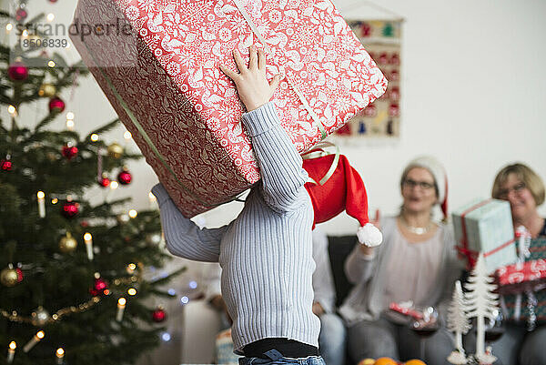 Kleiner Junge trägt zu Weihnachten einen großen Karton