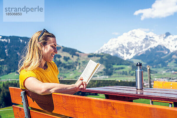 Junges schönes und glückliches Mädchen  das auf einer Bank ein Buch liest  Mounta