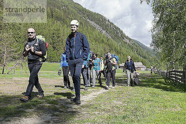 Gruppe von Kletterern wandert durch die Wiese in Richtung Klettergarten Oberried  Ötztal  Tirol  Österreich