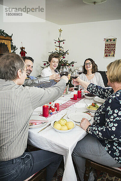 Familie klirrt während der Weihnachtsfeier zu Hause mit Weingläsern
