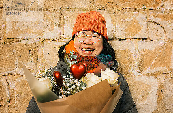 Fröhliches Porträt einer lächelnden Asiatin mit Valentinsblumen