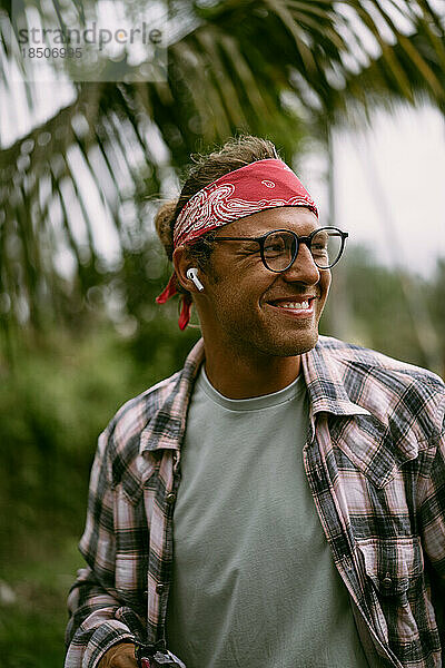 Junger stilvoller Hippie-Mann mit rotem Kopftuch und Brille. Inselleben