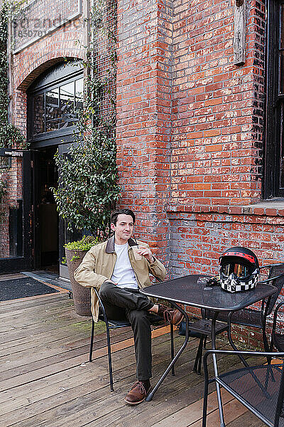 Friedlicher Mann sitzt in der Innenstadt am Bürgersteigstisch und trinkt Kaffee