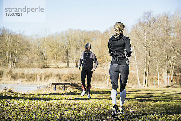 Mann und Frau joggen auf Fitnessparcours im Wald