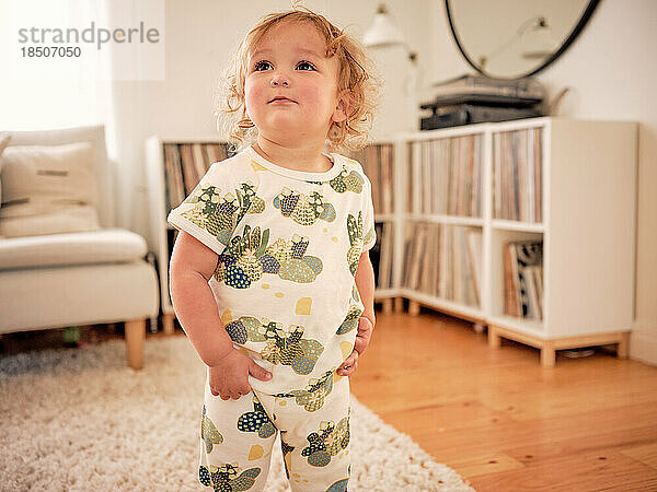 Grinning toddler in cactus clothes standing in family living room