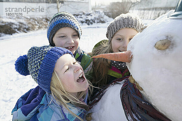 Kinder mit Schneemann auf Schneefeld