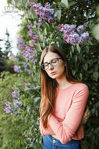 Junge braunhaarige Frau mit Brille und Pullover in einem Frühlingspark