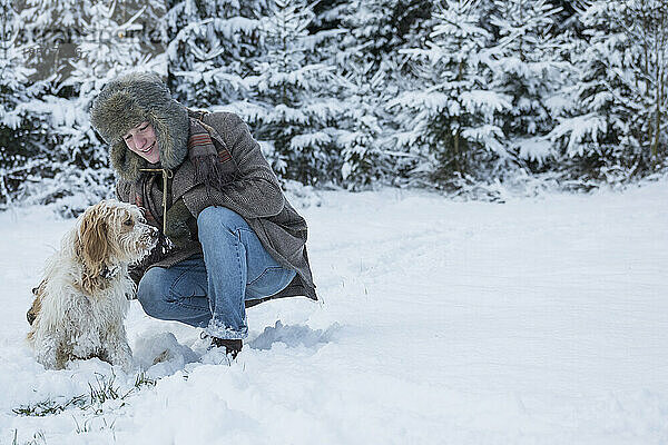 Junger Mann mit Hund in verschneiter Landschaft im Winter  Bayern  Deutschland
