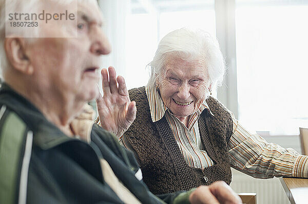Glückliche ältere Frau mit ernsthaftem Mann im Pflegeheim