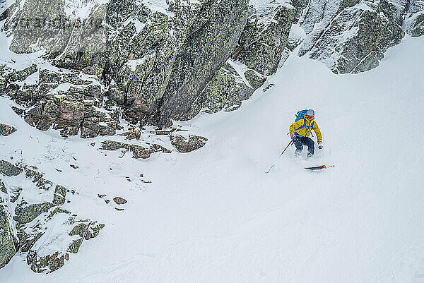 Backcountry-Skifahrer fahren Schnee mit hohen Felswänden auf jeder Seite