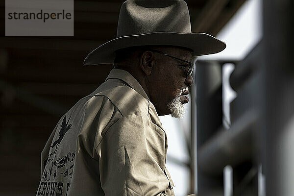 Ein in Licht und Schatten getauchter Cowboy beobachtet das Arizona Black Rodeo