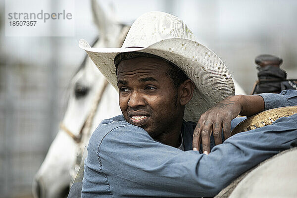 A cowboy leans on his horse at the Arizona Black Rodeo